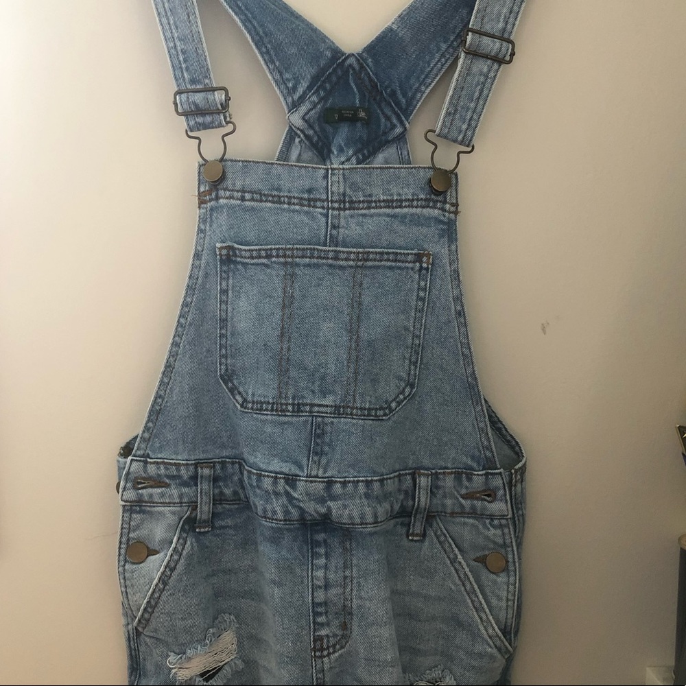 Lighter wash denim short overalls.
